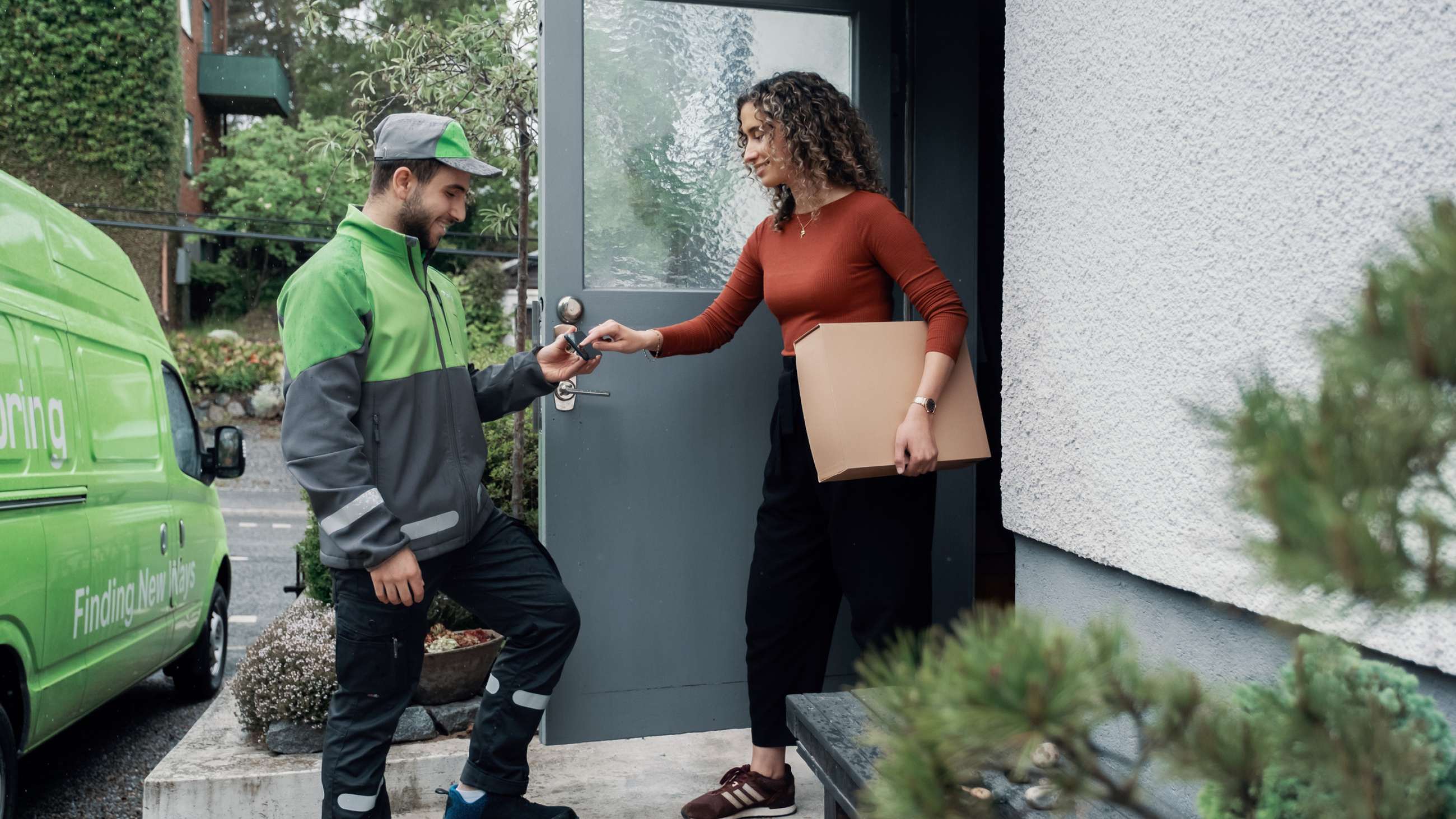 Ett Bringbud levererar ett paket till dörren hos en kvinna som signerar för leveransen på en telefon