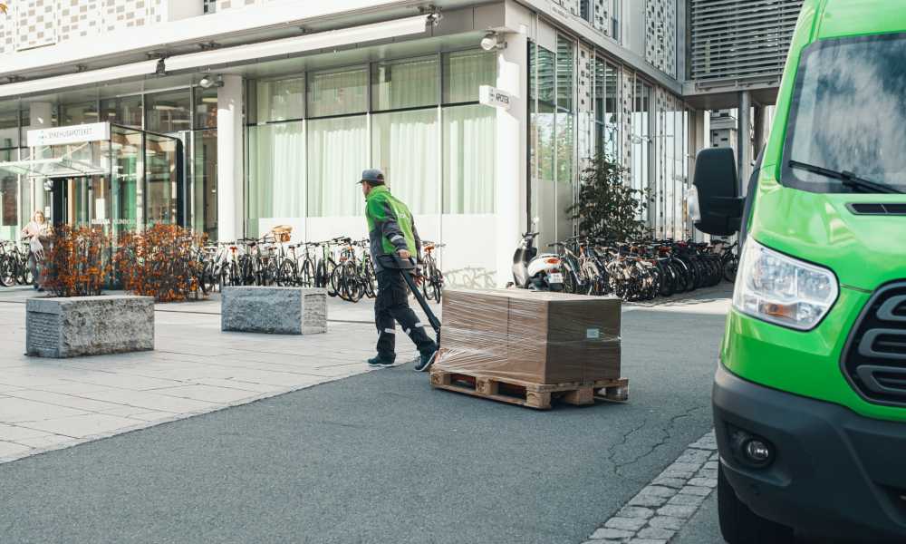 A Bring driver pulls a pallet jack with parcels to a company