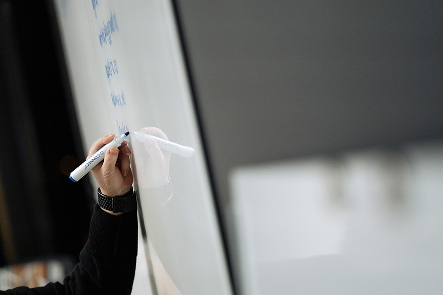 En hand skriver på en whiteboard-tavla