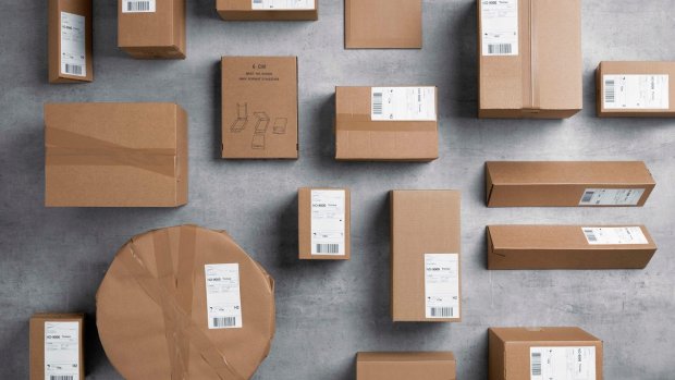 Många emballerade bruna paket i olika storlekar och former som ligger på en plan grå yta