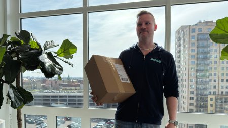 Eric Rydhög, TPL-ansvarig på Coolstuff, står med ett paket i handen framför fönster