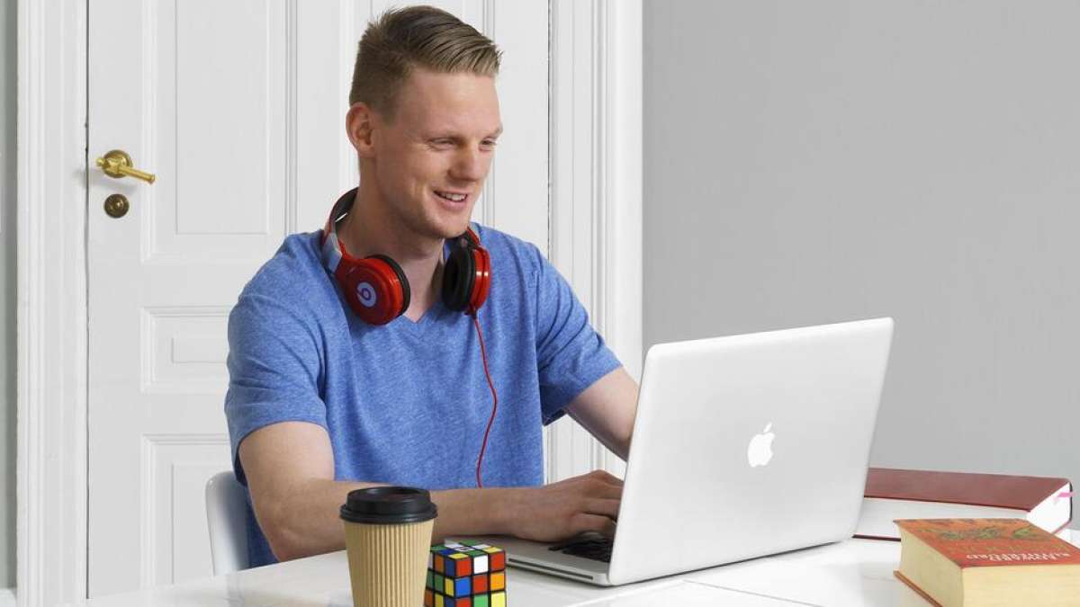 Glad kille sitter framför sin laptop