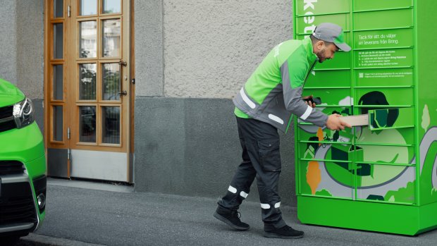 En Bringchaufför stoppar in ett paket i en lucka i en Bringpaketbox
