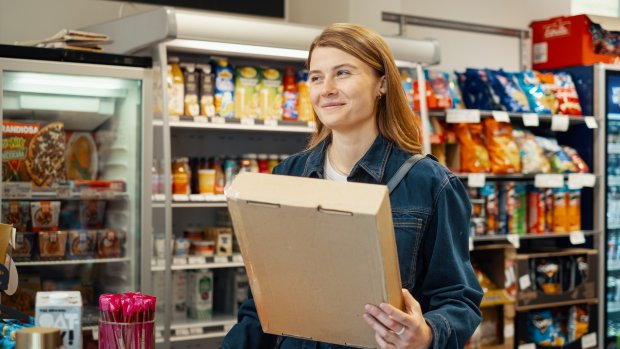 En kvinna står med ett paket i handen hos ett paketombud