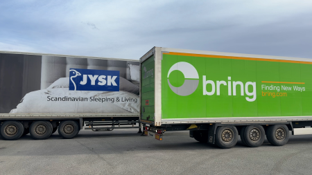 Två lastbilar står vid varandra, en med JYSK-logga på och en med Bring-logga på