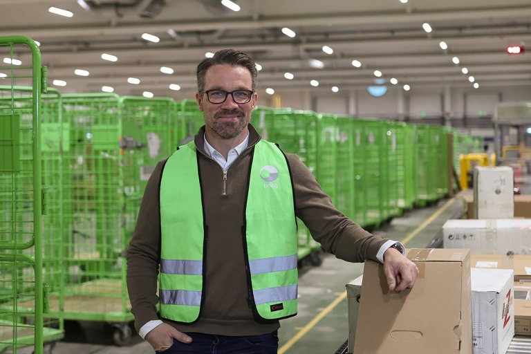 Lars Furunäs, distriktschef för terminal och distribution i Örebro och Linköping står framför flera paketburar på terminalen