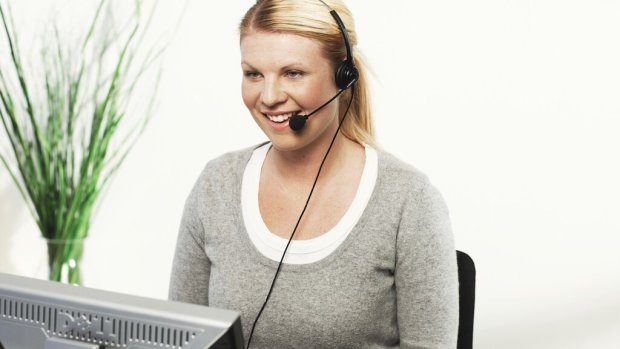 A woman is sitting in front of a pc talking in a headset.