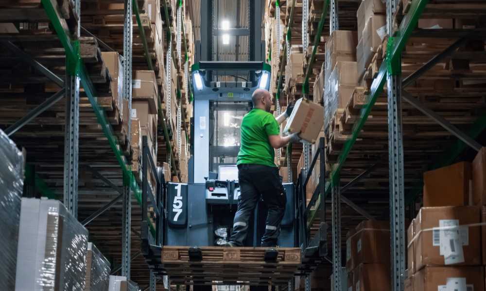 A man picks up a parcel in a warehouse standing on a truck