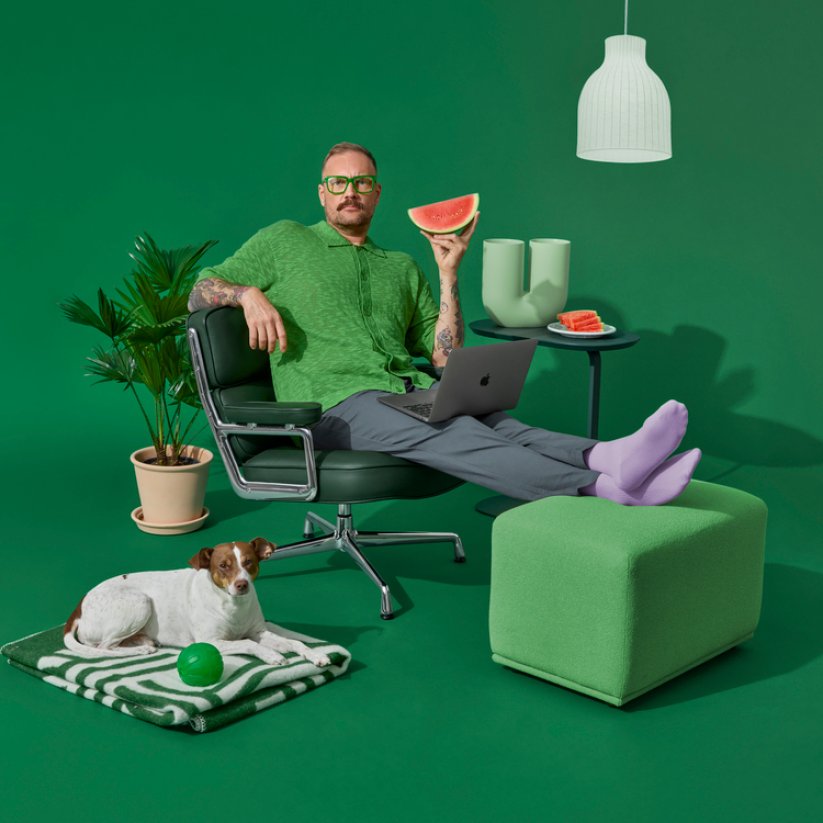 En man sitter i en stol, en hund ligger bredvid honom på golvet