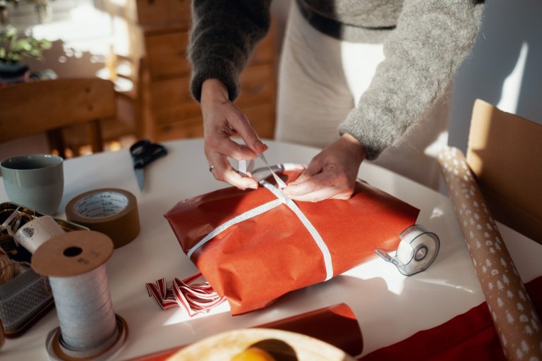 Två händer slår in en julklapp som är köpt i en webbutik
