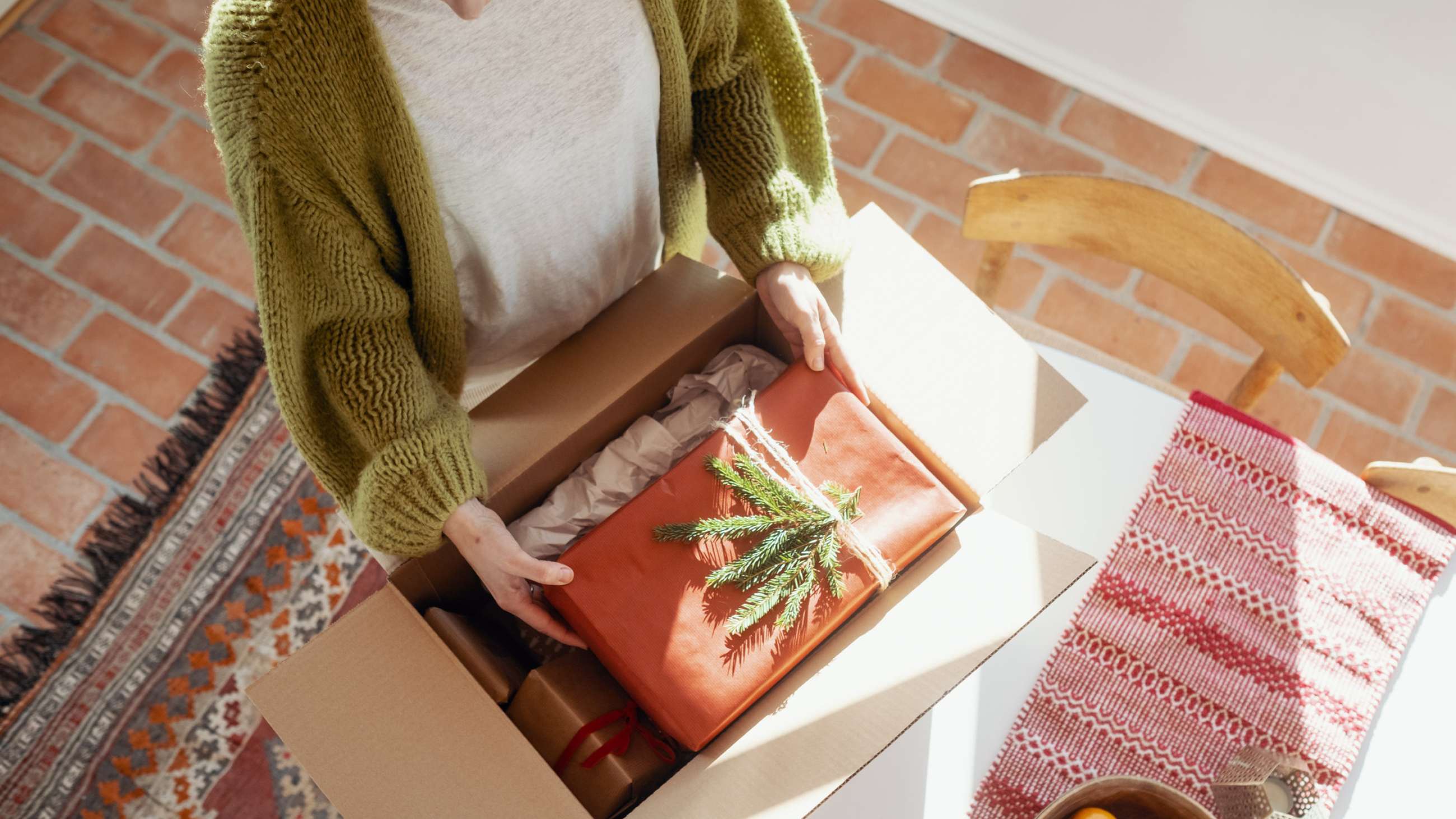 En kvinna lägger ner en julklapp i ett paket.