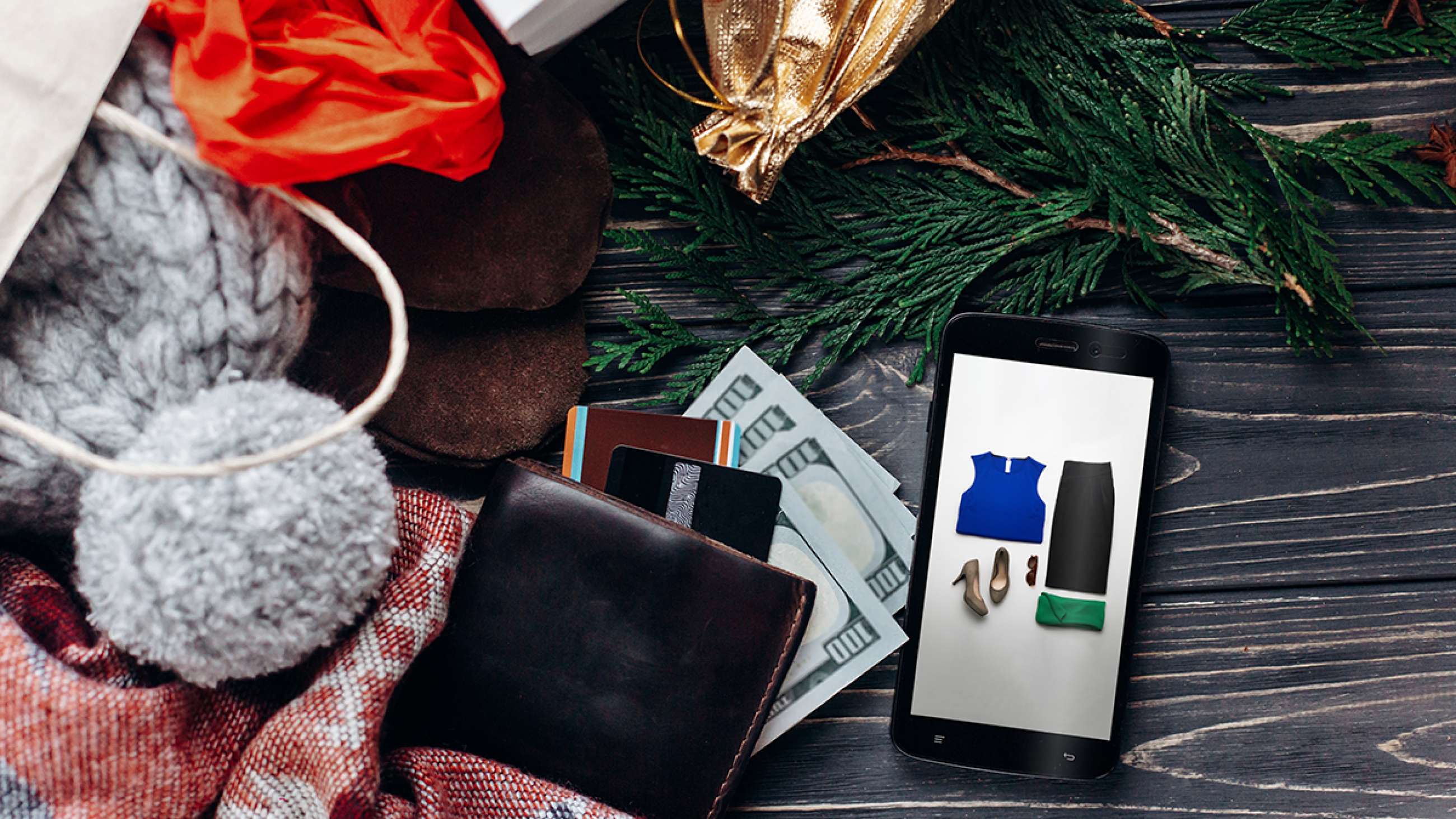 Plånbok med kreditkort, smartphone med kläder på displayen, grankvist