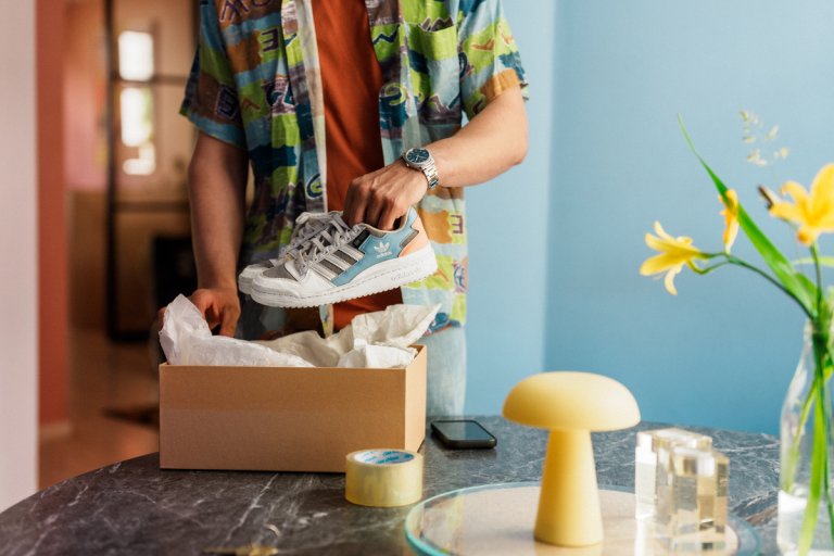 En kille packar ner ett par sneaker i ett paket.