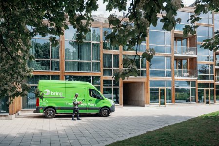 Grön budbil parkerad framför byggnad