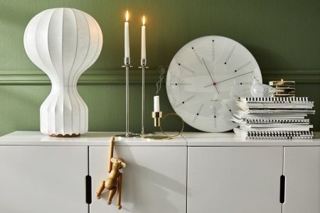 En byrå med ljusstakar, en lampa, en klocka och en hög med böcker på