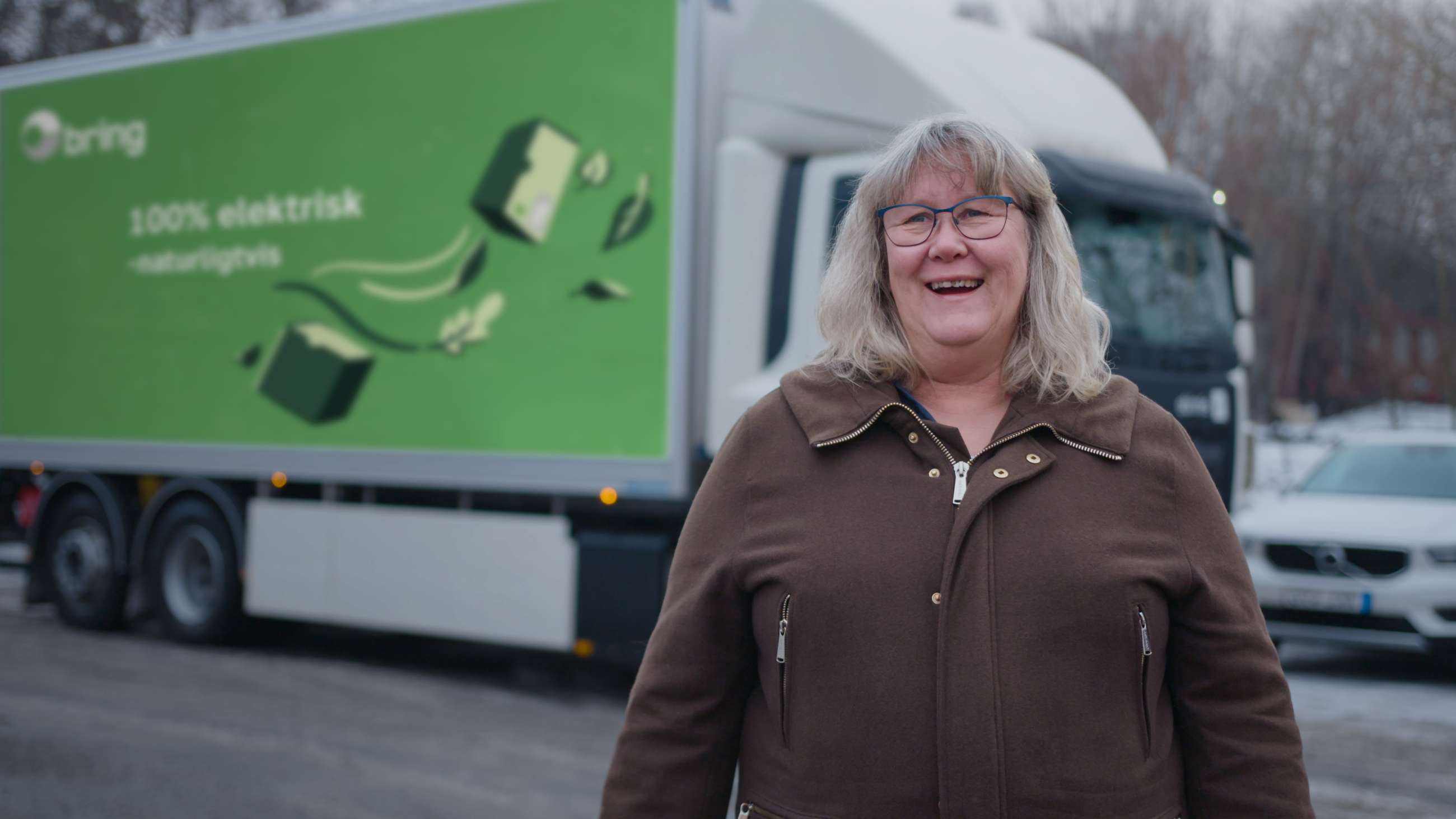 Catherine Löfquist, hållbarhetschef på Bring, står leende framför en elektrisk Bring lastbil