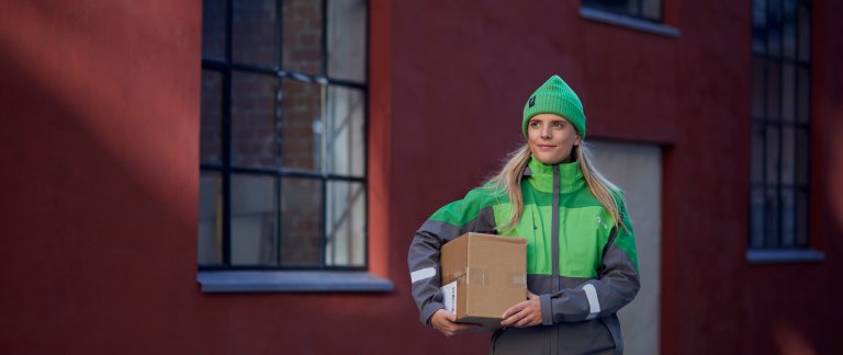 Kvinnlig Bringanställd bär ett paket