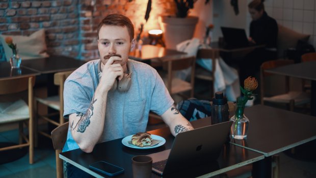 Ung kille sitter vid ett bort på ett café och blickar ut. 