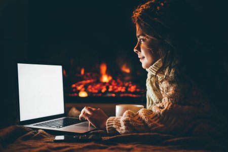 Kvinna shoppar online framför öppen brasa.