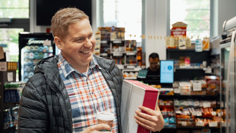 En man står inne hos ett Bringombud och håller i ett paket