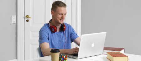 Glad kille sitter framför sin laptop