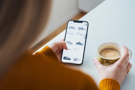 En kvinna har en mobil i handen med en webbutik och ska handla på nätet