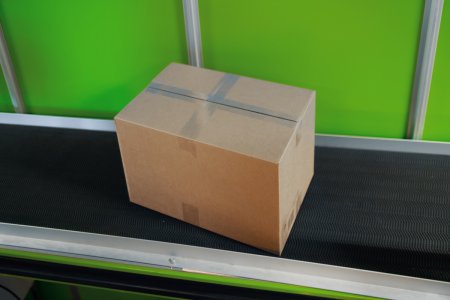 Ett igentejpat paket står på ett svart rullband