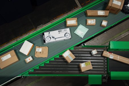 Flera paket åker på ett rullband på en terminal, sett uppifrån
