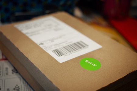 Ett paket med en grön klisterlapp på som säger Retur