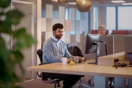 En man sitter på ett kontor vid ett skrivbord framför en dataskärm