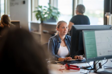 En kvinna sitter på ett kontor framför en dataskärm