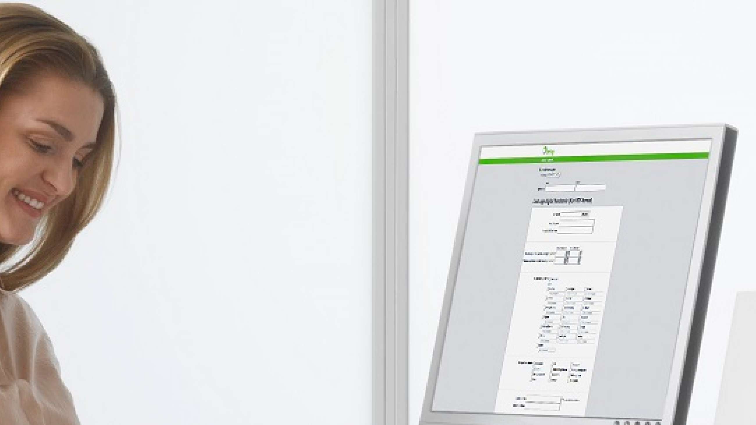 Leende kvinna som står framför en dataskärm