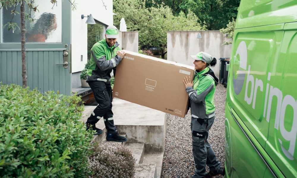 Två Bring chaufförer bär ett paket med en TV.