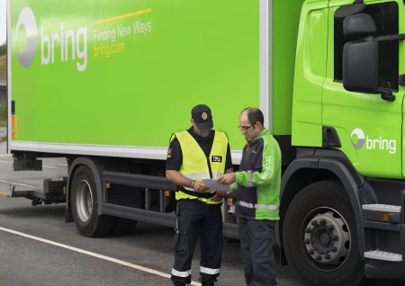 En Bring-chaufför visar tulldokument för personal.
