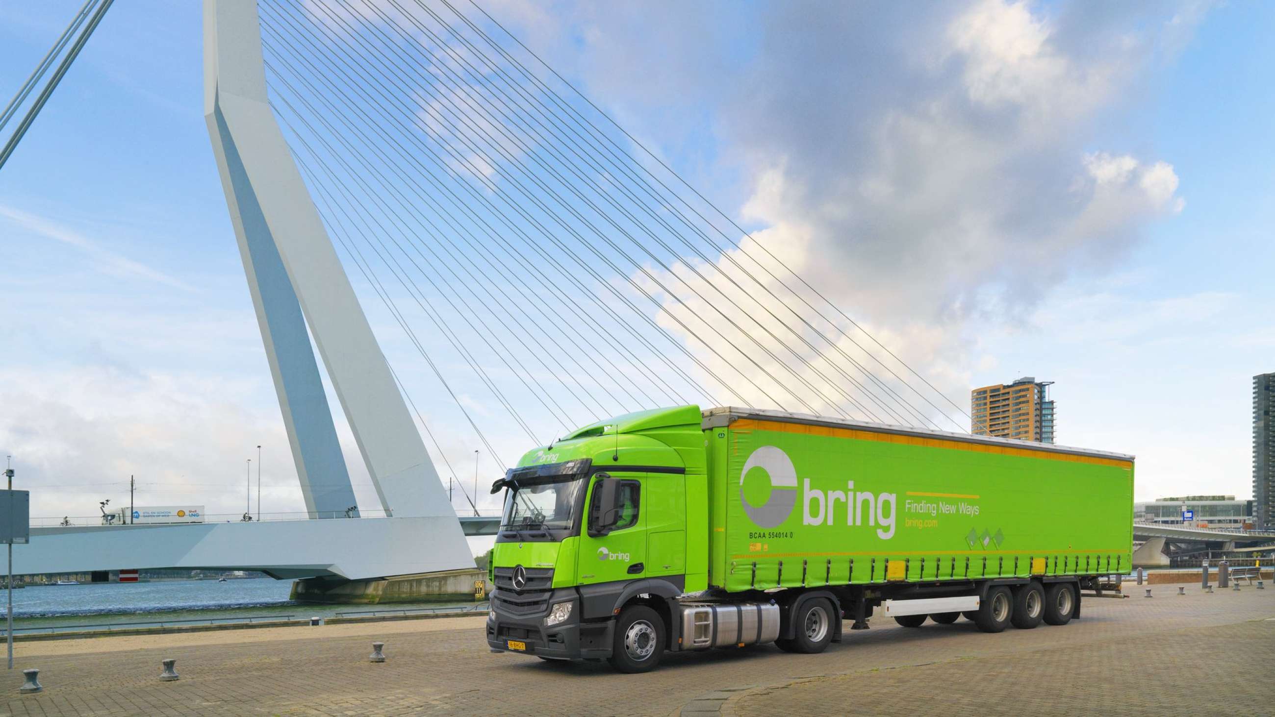 En Bring lastbil kör på en väg bredvid en bro