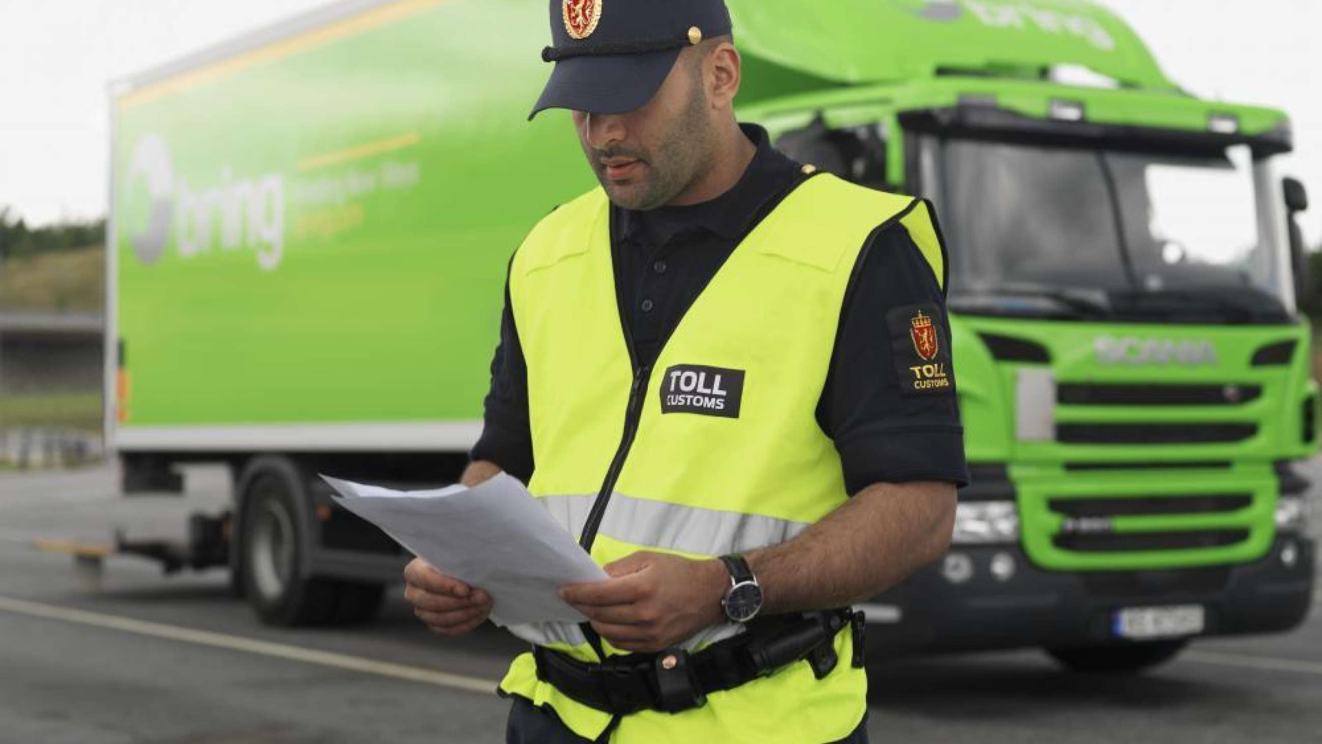 En tulltjänsteman läser igenom dokument framför en Bring lastbil.